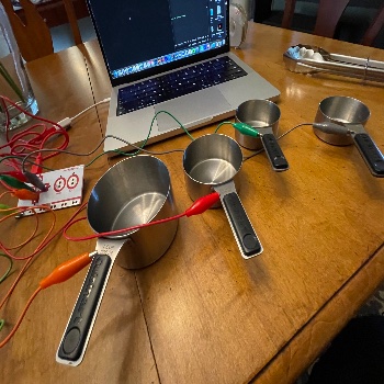 I connected the alligaor clips to the metal measuring cups and set up the circuit. On click, the particles would appear on the screen completing the physical and digital interaction.